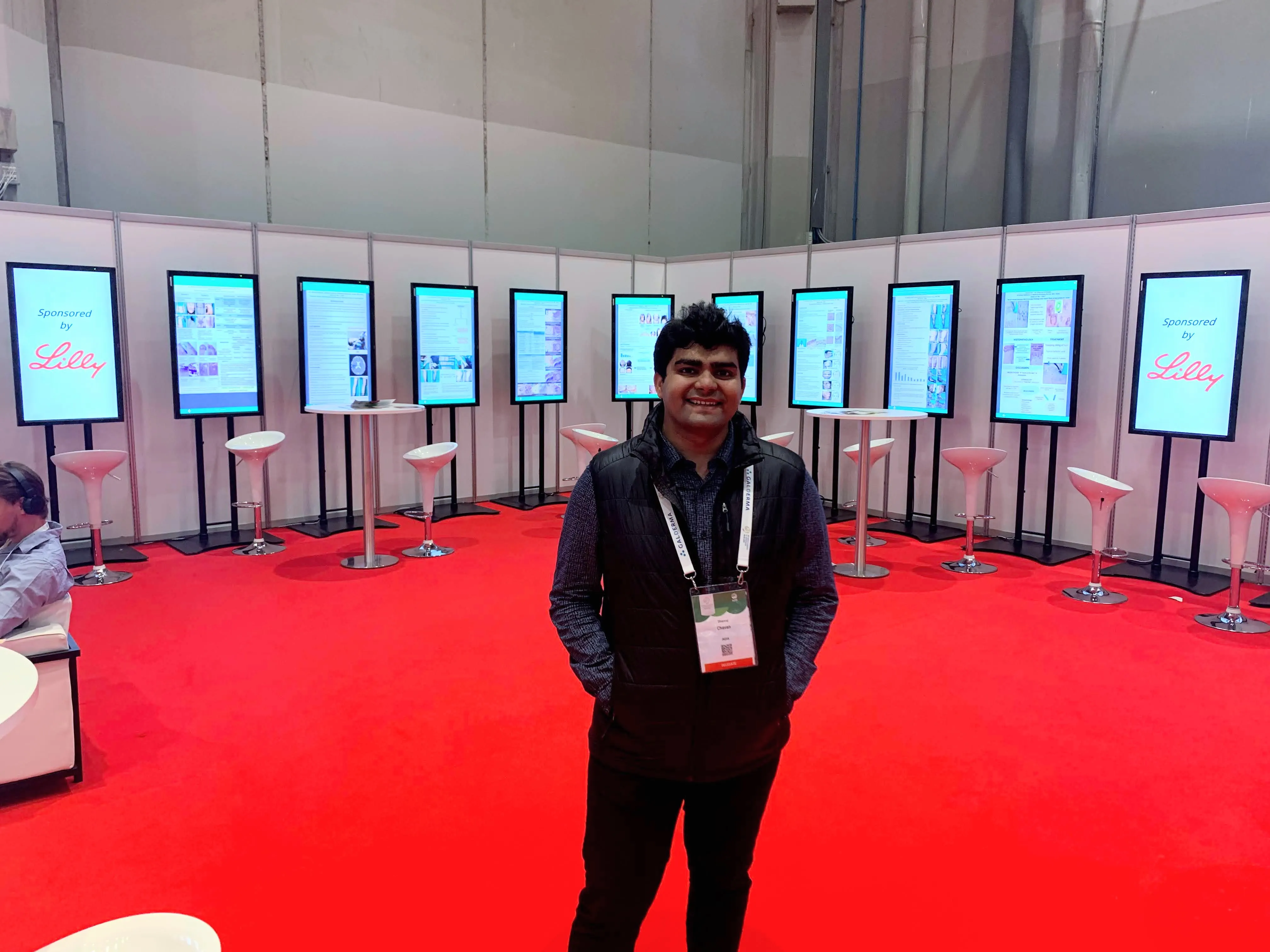 Dhanraj at the World Congress of Dermatology, Milan, with all nine of his accepted poster presentations on the screens behind him — June 2019